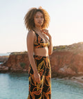 Gold Leaf bralette top drawn by Jenzahni Waina, worn with matching wide-leg pants on a coastal cliff